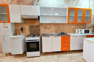 uma cozinha com electrodomésticos brancos e armários laranja em Moody & cozy 1br in city center em Luanda