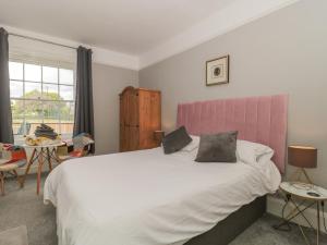 a bedroom with a large bed with a pink headboard at Buckland House Annex in Taunton