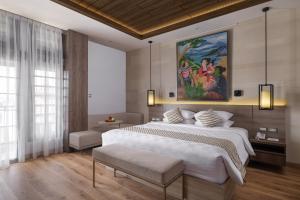 Un dormitorio con una cama grande y un cuadro en la pared. en The Margaux Hotel Yogyakarta, en Yogyakarta 69 fotos más