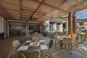 un patio con mesas y sillas en una terraza en The Margaux Hotel Yogyakarta, en Yogyakarta