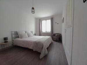 ein weißes Schlafzimmer mit einem Bett und einem Fenster in der Unterkunft gite de la tour carrée in Montrichard