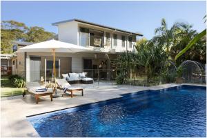 a house with a swimming pool in front of a house at Always Summer Boomerang in Boomerang Beach
