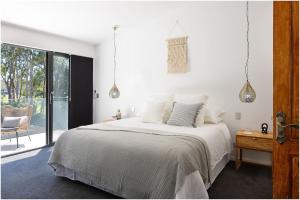 a white bedroom with a bed and a window at Always Summer Boomerang in Boomerang Beach +24 photos