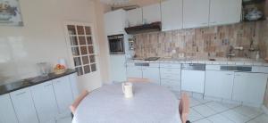 een keuken met een tafel en witte kasten bij L'Enclos des Lys -appartement in Aurillac