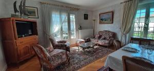 een woonkamer met een tafel en stoelen en een televisie bij L'Enclos des Lys -appartement in Aurillac