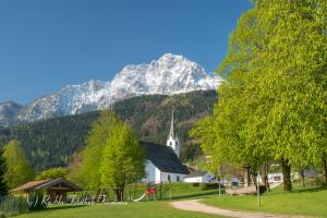 a white church with a mountain in the background at Ferienwohnung zum Kunstei in Anger