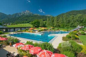 a swimming pool with red umbrellas in a resort at Ferienwohnung zum Kunstei in Anger