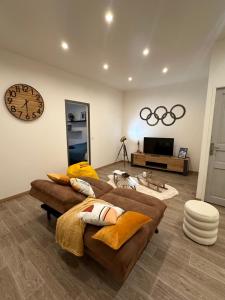 a living room with two couches and a clock on the wall at Le Refuge T3 centre ville 63m2 pied des montagnes in Albertville