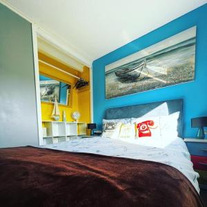 a bedroom with a large bed with blue walls at The Beach Hut in Scratby