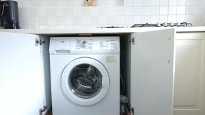 a white washing machine under a counter in a kitchen at huisje Zilvermeeuw in Burgh Haamstede