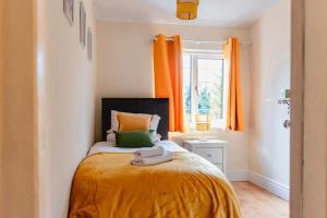 a bedroom with an orange bed and a window at Ilford - Driveway- 3 bed- M6 J6 Contractors & Families in Birmingham