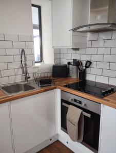 una cocina con armarios blancos y fregadero en Modern Apartment Nottingham en Nottingham