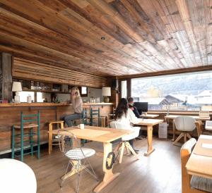 persone sedute ai tavoli di un ristorante con soffitti in legno di SoHome Le Chable a Le Châble