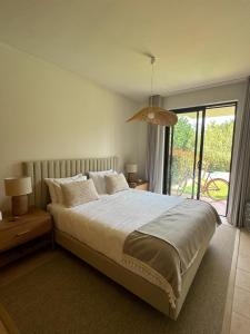 ein Schlafzimmer mit einem großen Bett und einem großen Fenster in der Unterkunft Villa Alvor piscina praia e golf in Alvor