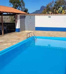 a blue swimming pool in front of a house at Pousada Pico do Papagaio in Aiuruoca