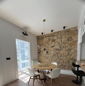 uma sala de jantar com uma parede de pedra e uma mesa e cadeiras em Piso nuevo-Plaza Armas em Ferrol