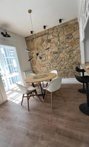 comedor con mesa, sillas y pared de piedra en Piso nuevo-Plaza Armas, en Ferrol