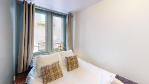 ein Bett mit zwei Kissen in einem Zimmer mit einem Fenster in der Unterkunft Le Tonnelier Strasbourgeois - Strasbourg Cathédrale in Straßburg