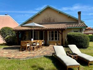 ein Haus mit einem Tisch, Stühlen und einem Sonnenschirm in der Unterkunft Ferienhaus mit Garten im Herzen von Lacanau-Océan in Lacanau-Océan