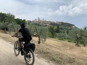 ガンバッシ・テルメにあるAppartamento con piscina Il Borghetto - vicino San Gimignanoの自転車に乗って未舗装の道を下る男