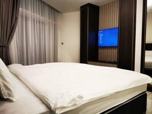 1 dormitorio con 1 cama blanca y TV en LikeHome - Amazing 2 BR With Burj Khalifa & Canal View, en Dubái