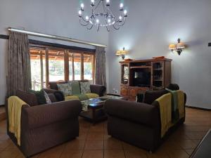 una sala de estar con 2 sofás y una lámpara de araña. en Glen Afric Country Lodge, en Hartbeespoort