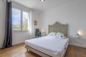 een slaapkamer met een bed met witte lakens en een raam bij Maison 12pers 3kms de la plage in Plozévet