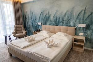 una camera da letto con un grande letto e un dipinto sul muro di Hotel Atlantis Wellness & Conference a Hajdúszoboszló