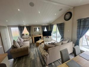 a living room with couches and a clock on the wall at Indulgence lakeside lodge i1 with hot tub, private fishing peg situated at Tattershall Lakes Country Park in Tattershall