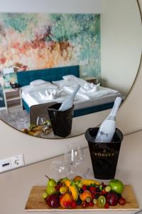 una mesa con copas de fruta y vino y un espejo en Hotel Atlantis Medical, Wellness & Conference, en Hajdúszoboszló