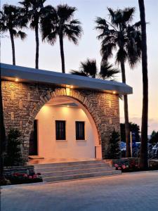 a building with an archway in front of palm trees at Sveltos Hotel in Larnaca