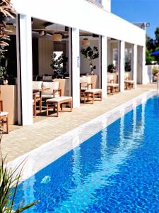 una piscina frente a un hotel con mesas y sillas en Sveltos Hotel, en Lárnaca