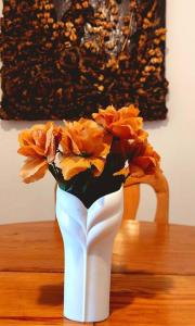 a white vase filled with orange flowers on a table at Pet friendly T1 sossegado c/ pátio espaçoso in Luanda