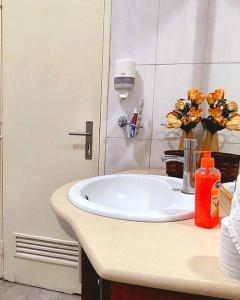 a bathroom with a sink and flowers on a counter at Pet friendly T1 sossegado c/ pátio espaçoso in Luanda