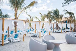 un grupo de sillas y mesas en la playa en Residences by Playa Caracol Residences en El Quindio