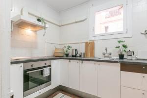 a white kitchen with white cabinets and a window at VEGUER in Barcelona
