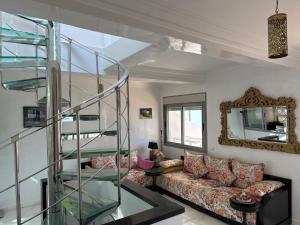 a living room with a couch and a glass staircase at LOCATION HICHAM in Tangier