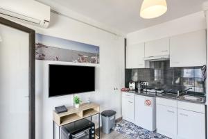 a kitchen with white cabinets and a flat screen tv at Casa Jois in Empuriabrava