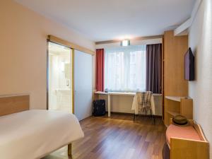 a hotel room with a bed and a window at ibis Stuttgart Centrum in Stuttgart