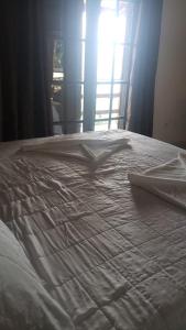 Cama blanca con sábanas blancas y ventana en Pousada Cantinho D'Abrantes - Próximo as Melhores Praias de Ilhabela - Veloso e Curral, en Ilhabela