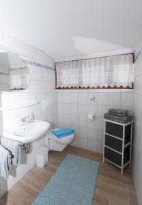 a white bathroom with a sink and a toilet at Ferienwohnungen „Zum Bauern“ in Oberaudorf +22 photos