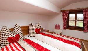 um quarto com duas camas com capas vermelhas e brancas em Ferienwohnungen „Zum Bauern“ em Oberaudorf