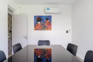 ein Besprechungsraum mit einem Tisch mit Stühlen und einem Gemälde in der Unterkunft The Acacia Village in Ciudad Lujan de Cuyo + 72 Fotos