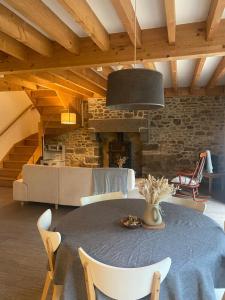 une salle à manger avec une table et une cheminée dans l'établissement Les Maisons du Tuly - Maison en Pierre, au Tronchet