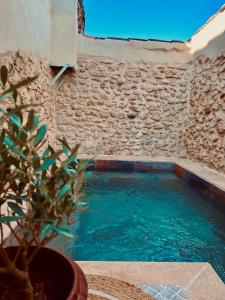 - une piscine dans un bâtiment avec un mur en pierre dans l'établissement La maison du Bougainvillier 10 personnes, à Dions