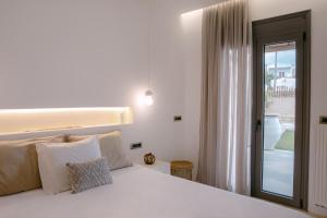 a white bed with white pillows in a bedroom at Villa Aldea - Luxury Boho Style in Melidhónion