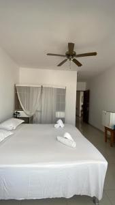 a bedroom with a large white bed with a ceiling fan at Maison Residencial casa de ferias in Santa Cruz