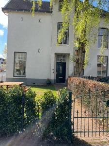 a white house with a fence in front of it at Luxe kamer in stadsvilla, gratis parkeren! in Apeldoorn