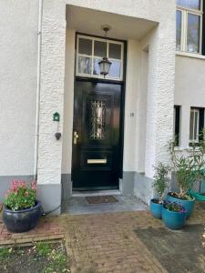 a black front door of a house with potted plants at Luxe kamer in stadsvilla, gratis parkeren! in Apeldoorn