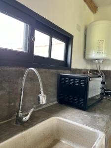Una encimera de cocina con fregadero y microondas. en El Garzal, en Mercedes